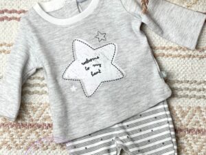 Preemie two piece sleeper set with a gray long sleeve top with a large star decal on the chest with gray and white striped gaiters with a tiny star print on a neutral background.