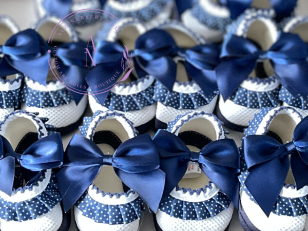 A collage of white soft sole baby shoes with a royal blue and white polkadot ruffle trim with satin bow for a buckle