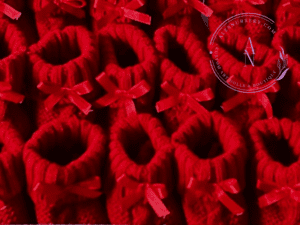 A collage of red cable knit baby booties with satin bows.