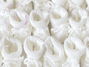 A collage of white knitted newborn baby booties with the cuff turned down and a bow tie.