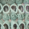 A collage of sage green knitted newborn baby booties.