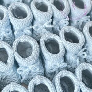 A collage of newborn baby blue spanish style knitted baby booties with a turned down cuff and bow.