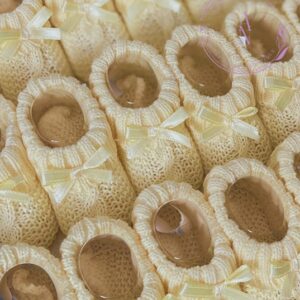 A collage of soft lemon yellow knitted newborn baby booties in a twisted pattern.