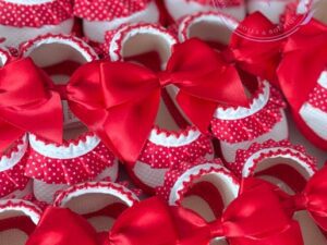 A collage of spanish styled Red and white ruffled soft baby shoes with large satin bows