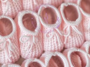 Soft pink colored knitted newborn baby booties made in Spain, sold by Alz's Baby Boutique