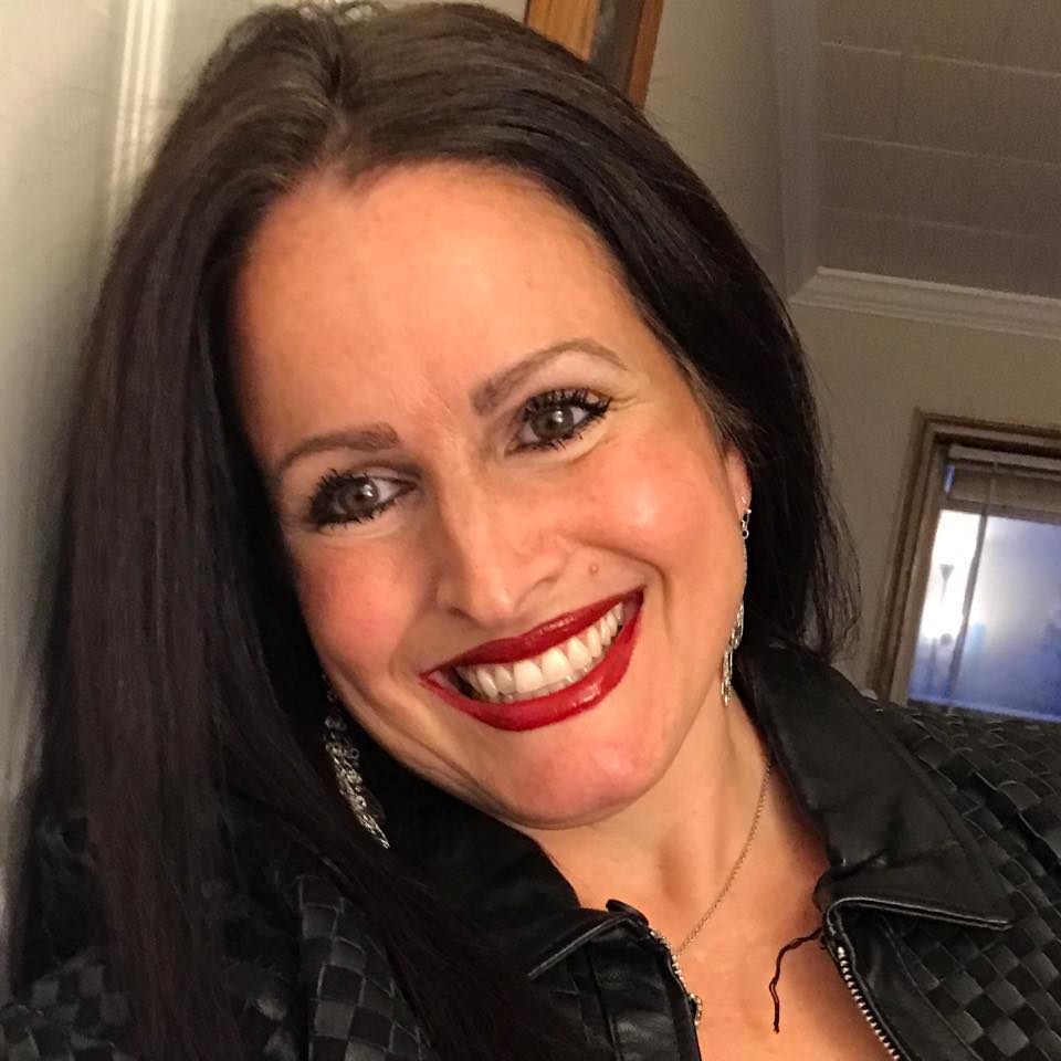 A lady smiling with long dark hair and red lipstick