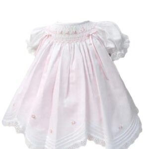 This is an absolutely precious white with pink scalloped dress with the daintiest embroidered white pink flowers over the smocking. This adorable baby dress has gathered puffed and ruffled short sleeves. Trimmed with the sweetest white lace scallop border, pink and white satin bow details. The most precious and elegant rows of pin tucks make this dress simply stunning. 65% polyester 35% cotton Made in Columbia Size- Preemie Sold by Alz's Baby Boutique