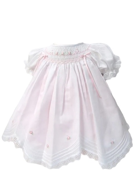 This is an absolutely precious white with pink scalloped dress with the daintiest embroidered white pink flowers over the smocking. This adorable baby dress has gathered puffed and ruffled short sleeves. Trimmed with the sweetest white lace scallop border, pink and white satin bow details. The most precious and elegant rows of pin tucks make this dress simply stunning. 65% polyester 35% cotton Made in Columbia Size- Preemie Sold by Alz's Baby Boutique