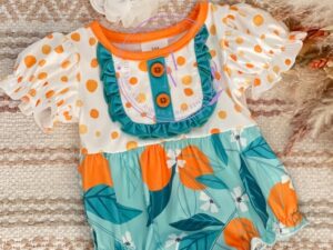 This adorable baby ruffle romper has the cutest white and orange polka dotted printed top trimmed with a beautiful teal blue ruffle and buttons. Having the sweetest gathered ruffled short sleeves. The dark and light teal blue bottoms have an orange and white floral print with large leaves and ruffled legs. 95% Polyester  5% Spandex  Size 6m, 12m Sold by Alz's Baby Boutique