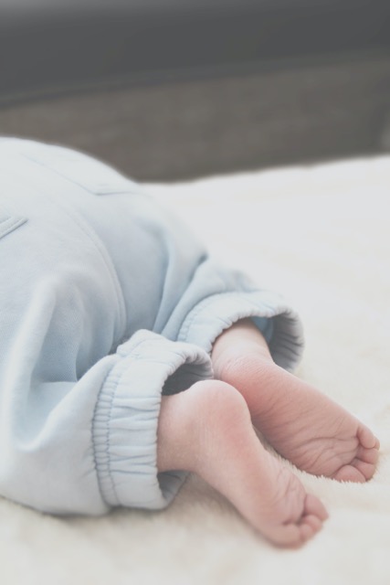 Baby's bottom wearing blue pants with bare feet crawling